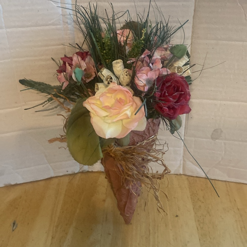Floral Wall Sconce with Pink and Red faux Flowers Container is cone shaped.